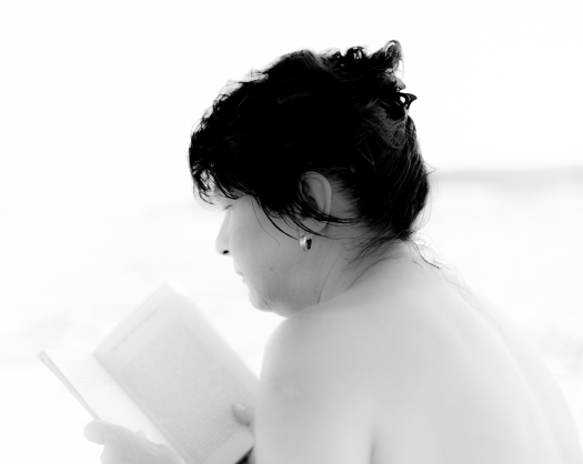 black and white image of woman reading on beach